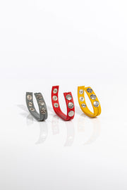 A product photo of three solid coloured leather cockrings.